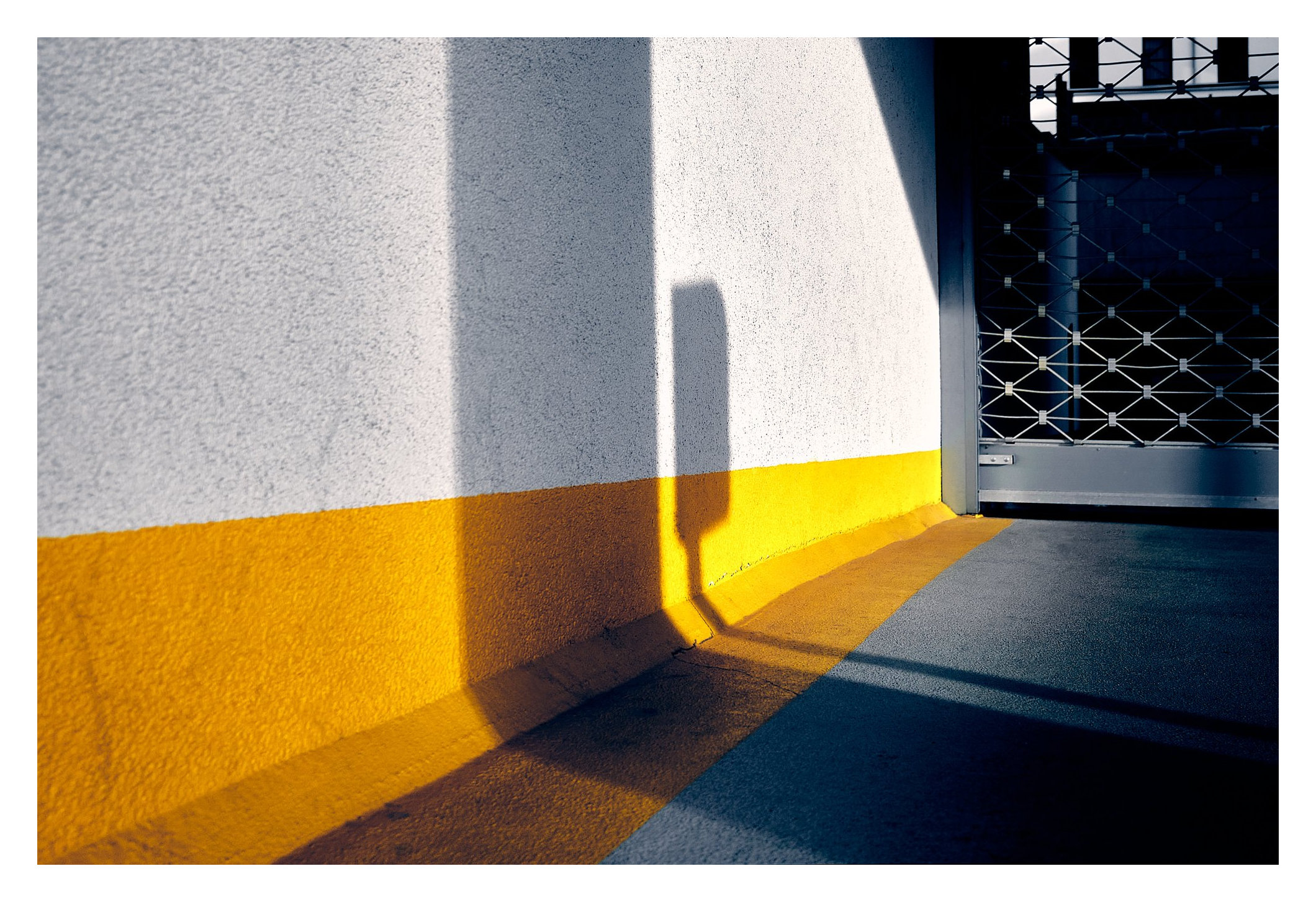 Gelber Wandstreifen und Schatten an einer Hofeinfahrt