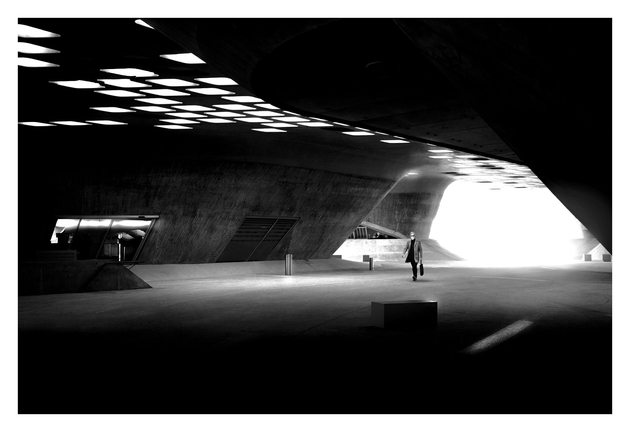 Kleine Person in einer großen futuristischen Halle in Schwarzweiß