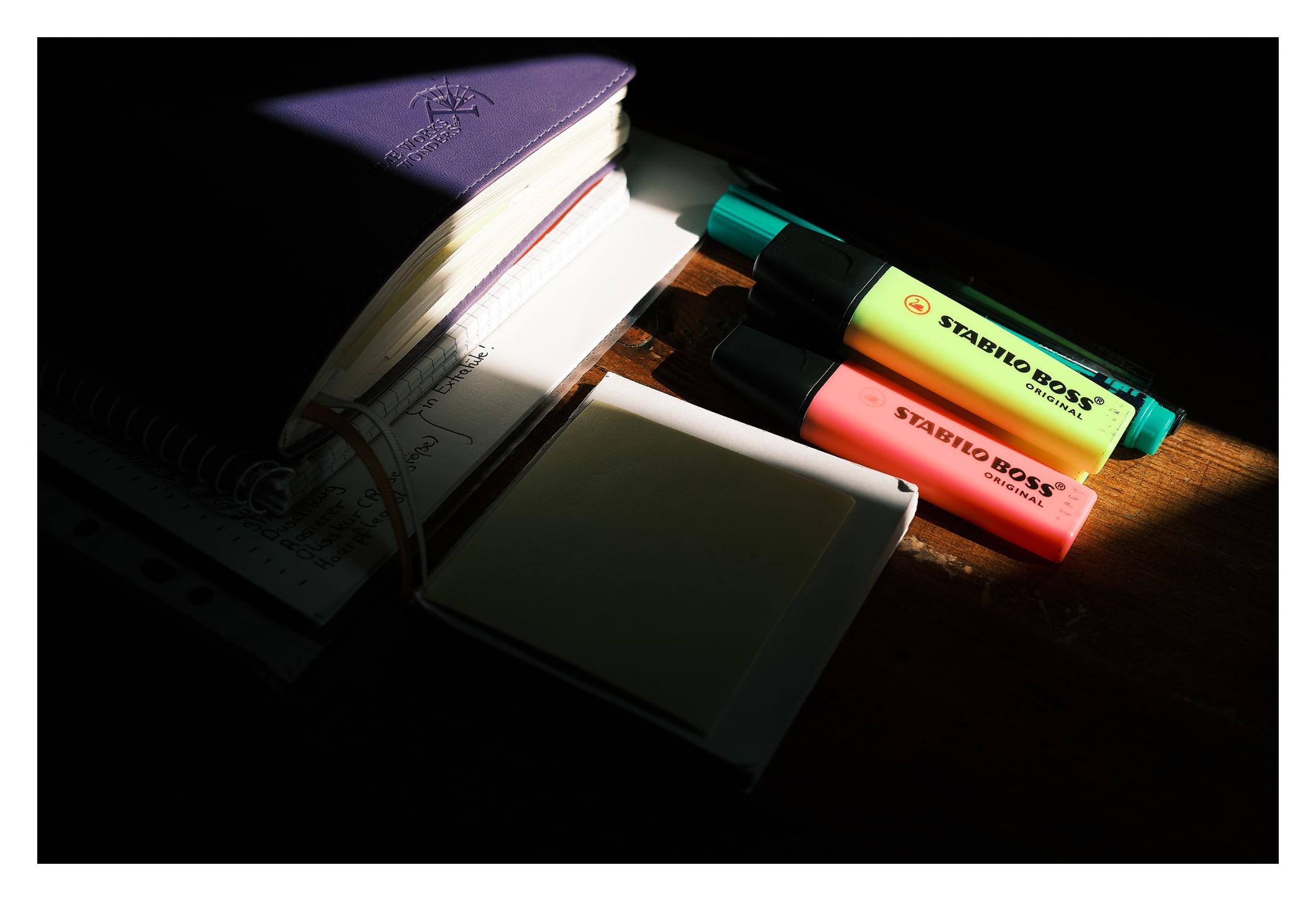 Notizbuch und Textmarker im Sonnenlicht auf einem alten Schreibtisch